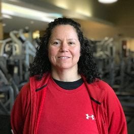 Phyllis Besso posing for a portrait in front of the fitness floor.